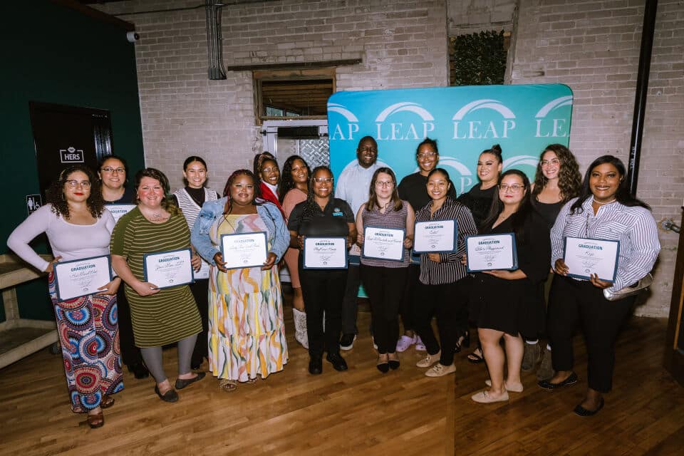 LEAP's One & All cohort 11 group stand holding their certificates of program completion at the graduation celebration event.