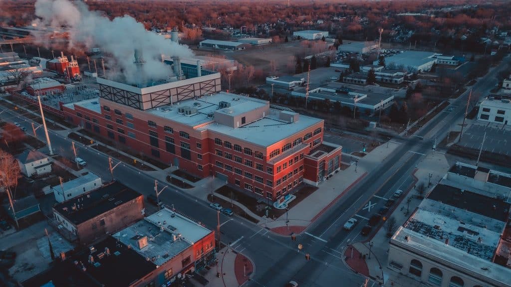 Aerial view of the BWL REO Town Plant in Lansing, featuring the brick power station and steam rising from its stacks at sunset.