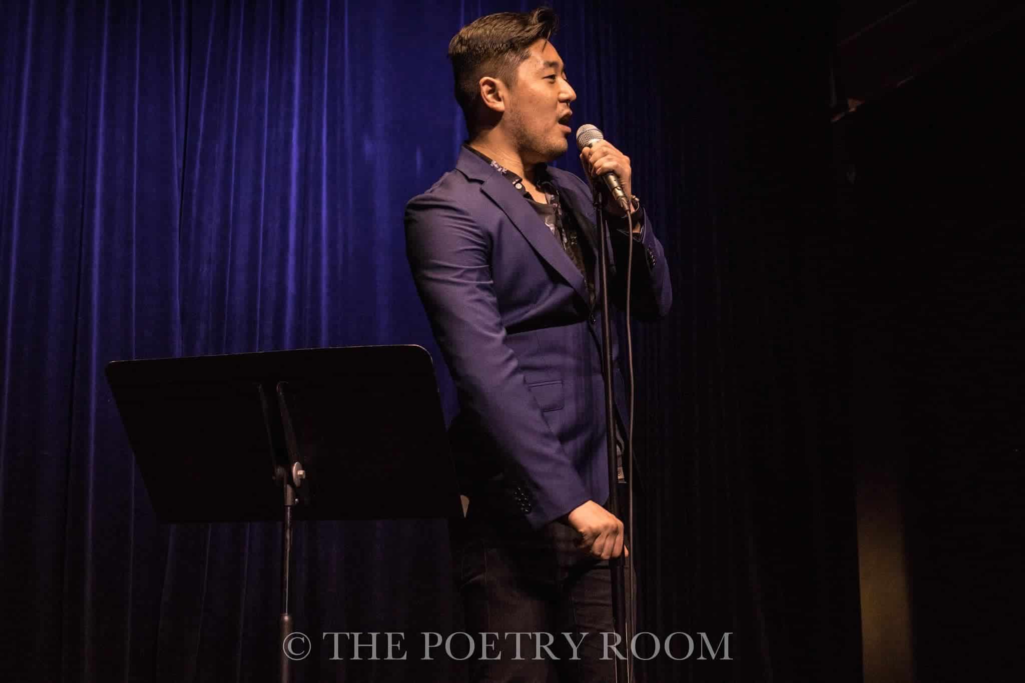 A photo of newly appointed Lansing Poet Laureate Masaki Takahashi performing at The Poetry Room in Lansing, MI for visual interest