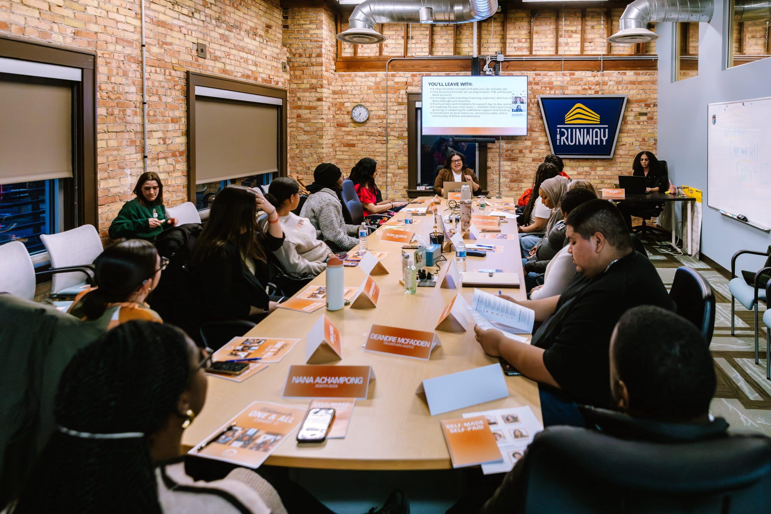 A group of people attending a professional workshop in a modern industrial conference room with exposed brick walls.