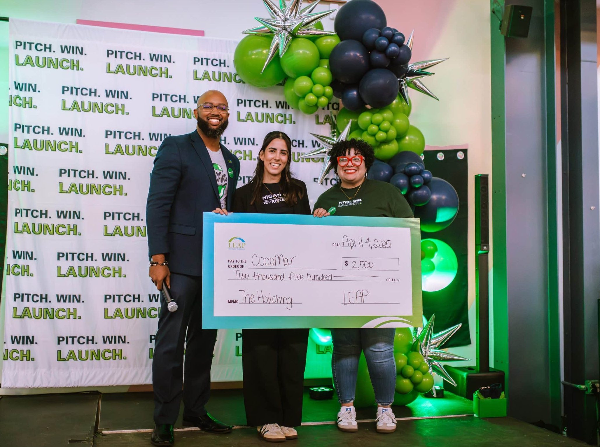 The Hatching pitch competition winner, CocoMar, holds a $2,500 ceremonial check from LEAP on stage.